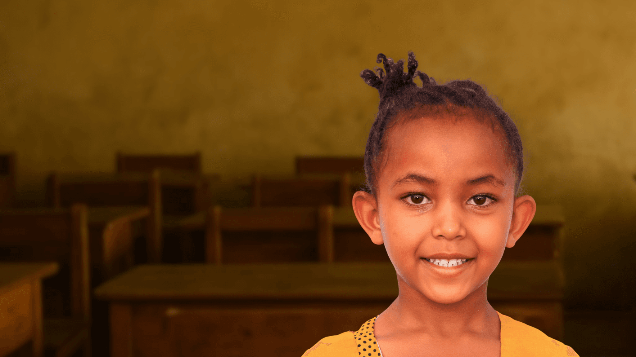 A child smiling in a classroom, representing BTO's expanding humanitarian reach